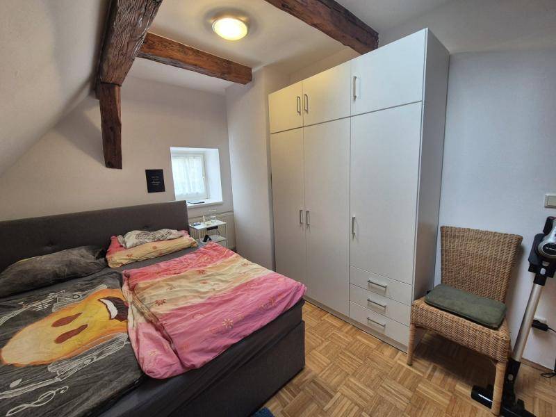 Schlafzimmer mit großem Kleiderschrank, Doppelbett und Holzbalken im Dachgeschoss, bietet viel Stauraum.