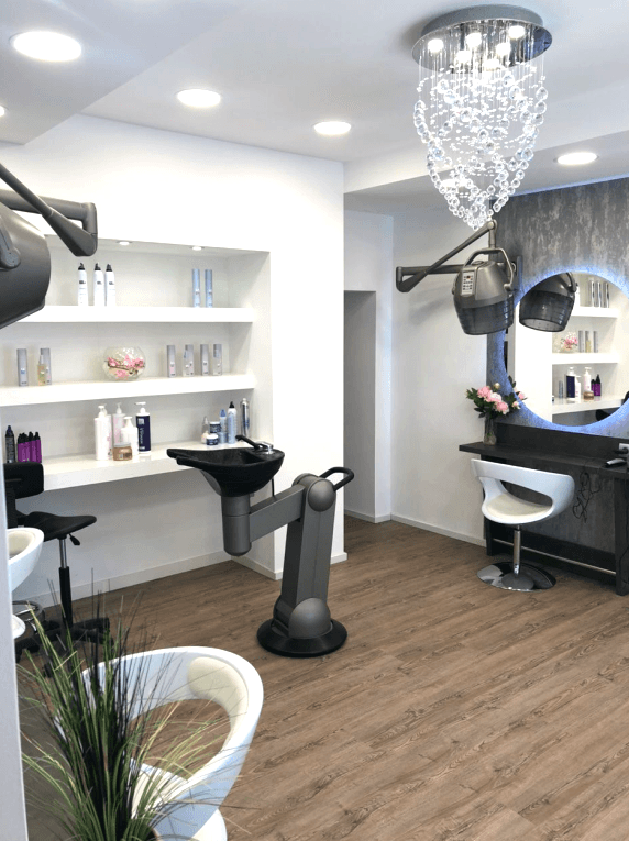 Heller Friseursalon mit modernem Waschbecken, Produktregalen und stilvoller Einrichtung, gut beleuchtet.
