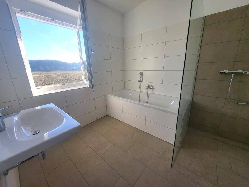 Helles Badezimmer mit Badewanne, Waschbecken und Fenster, das viel Licht spendet.