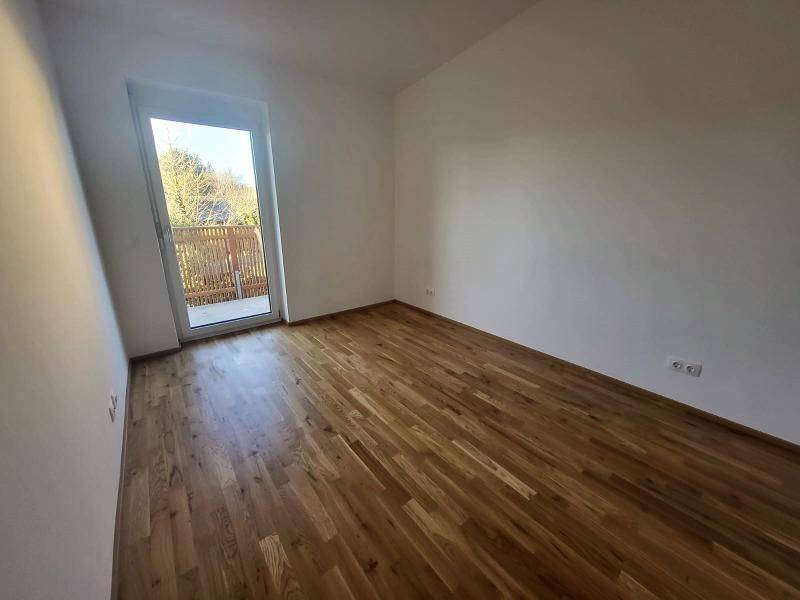 Geräumiges Schlafzimmer mit Holzboden und Balkontür, die viel Licht spendet.