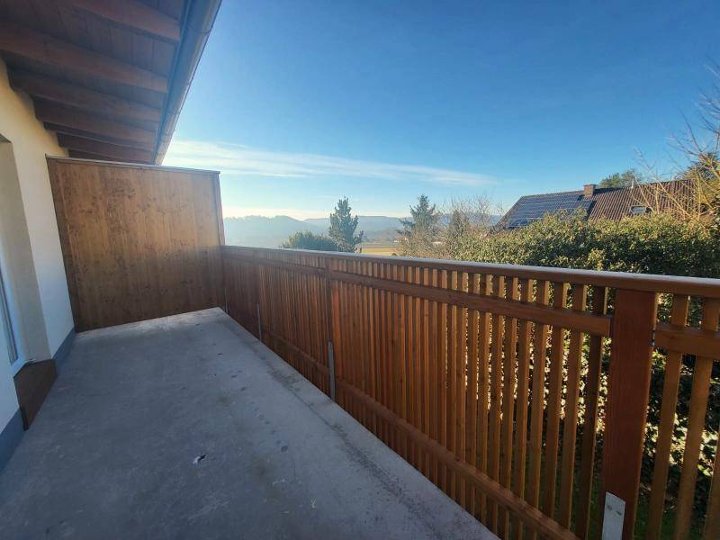 Balkon mit Holzgeländer und weitem Blick auf die umliegende Landschaft und Berge.