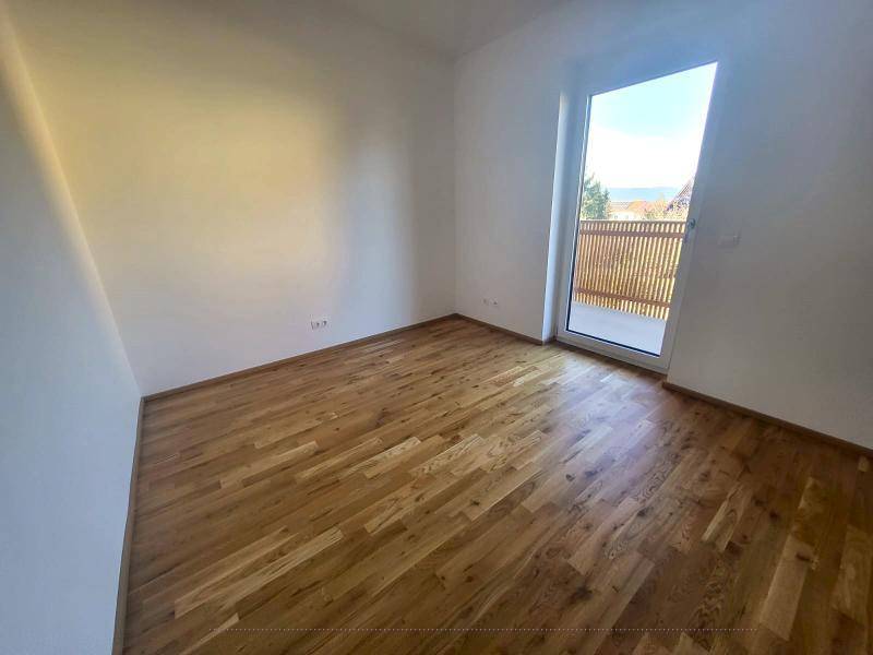 Schlafzimmer mit Holzboden und Balkonzugang, bietet einen weiten Blick auf die Umgebung.