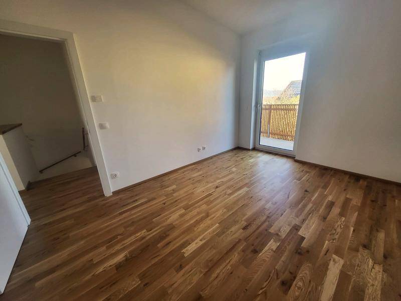 Helles Schlafzimmer mit Holzboden und Zugang zu einem Balkon, bietet viel Tageslicht.