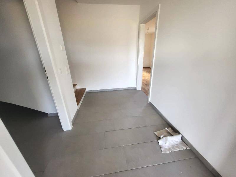 Flur mit Fliesenboden und Zugang zu verschiedenen Räumen und der Treppe.