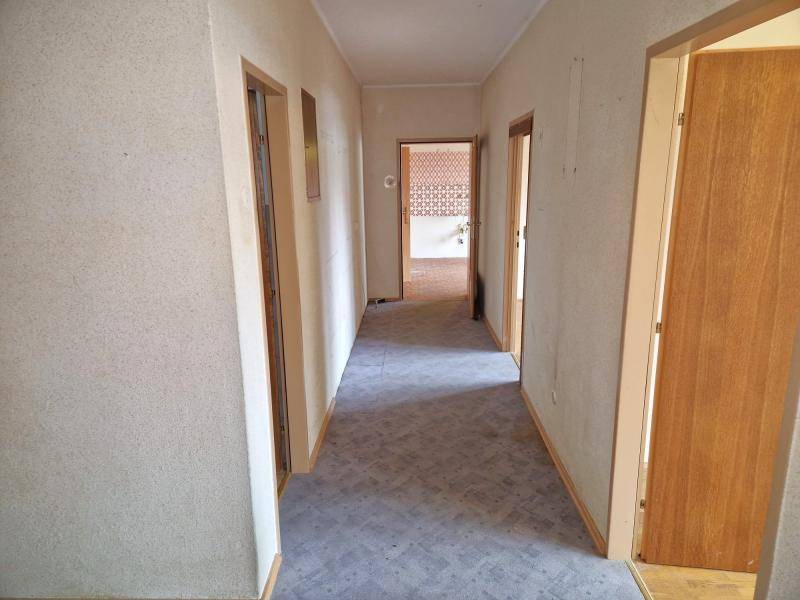 Langer Flur mit gemustertem Teppichboden und mehreren Holztüren zu angrenzenden Räumen.