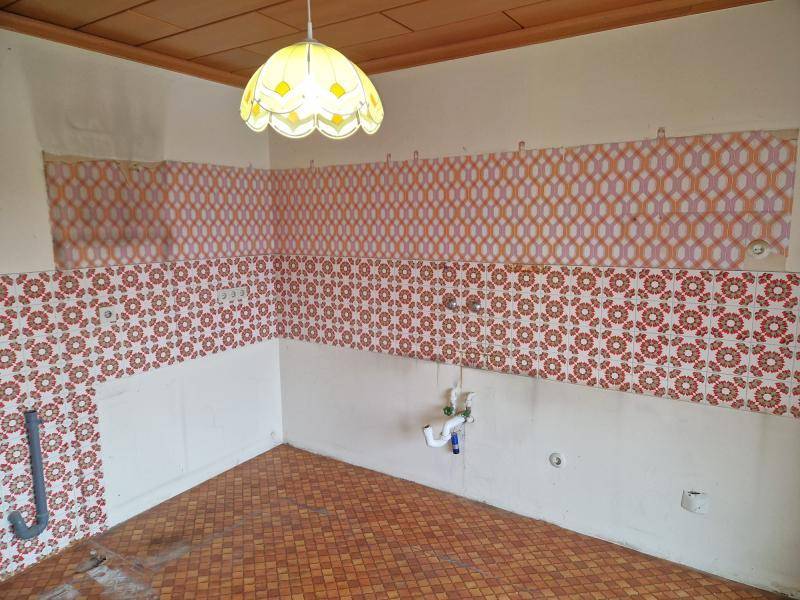 Leere Küche mit farbenfrohen Fliesen an Wänden und Boden, wartet auf eine moderne Ausstattung.