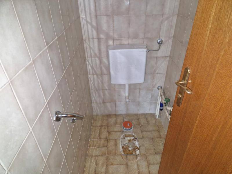 Separate Toilette mit hellen Fliesen und einem kleinen Fenster für natürliche Belüftung.