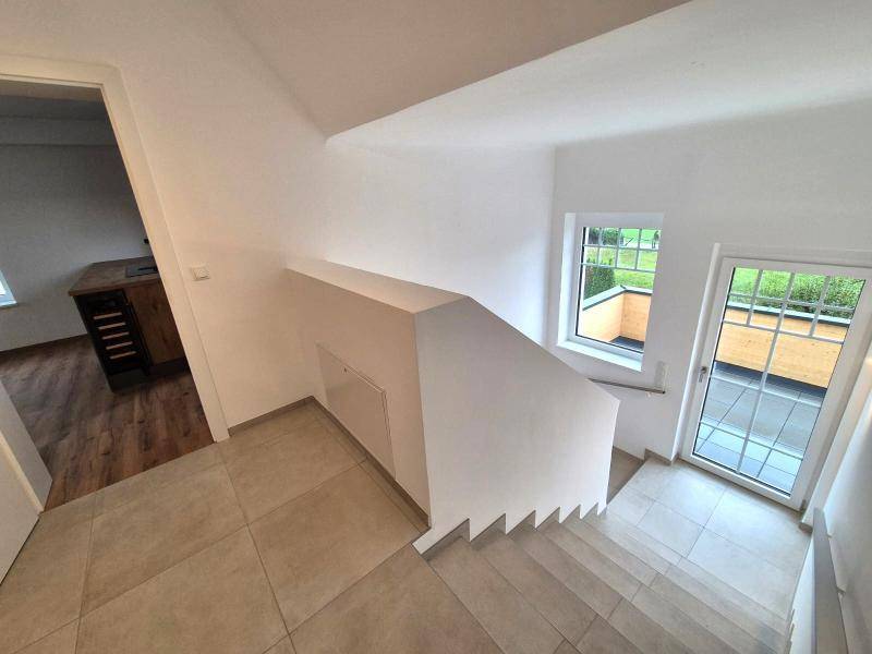 Heller Flur mit Treppe und Zugang zum Außenbereich, ausgestattet mit Fliesenboden.