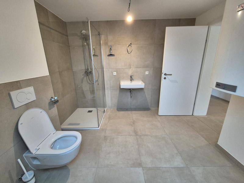 Modernes Badezimmer mit ebenerdiger Dusche, wandhängendem WC und schwebendem Waschbecken.