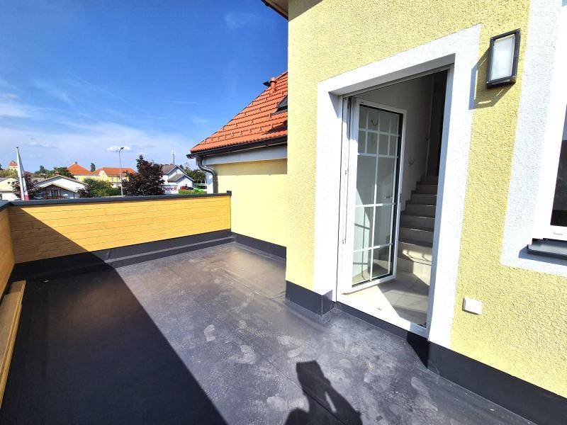 Zugang zur Dachterrasse mit gelber Fassade und Blick auf die Nachbarschaft unter blauem Himmel.