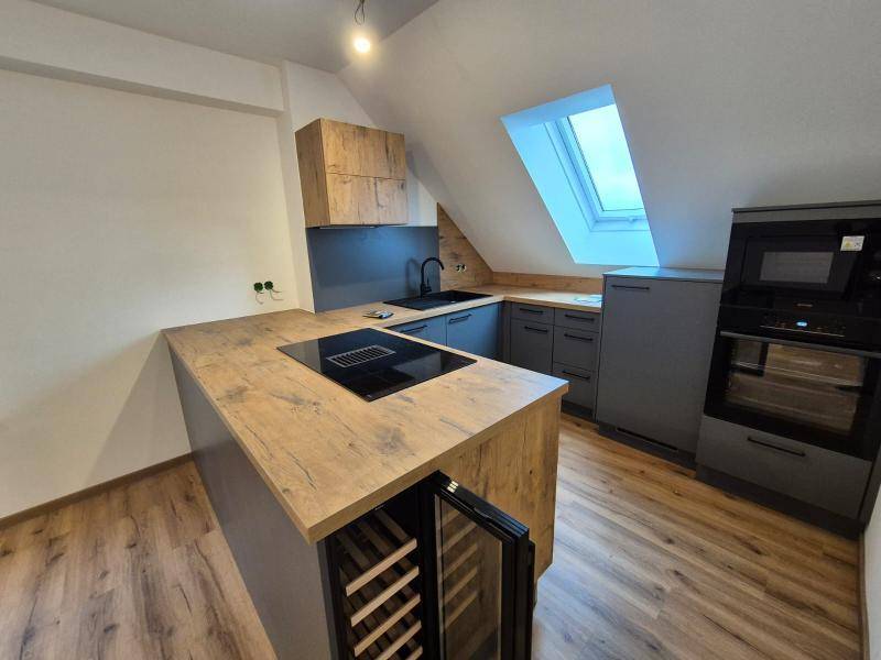 Moderne Küche mit integriertem Backofen, Mikrowelle und Weinkühler, unter einem Dachfenster gelegen.