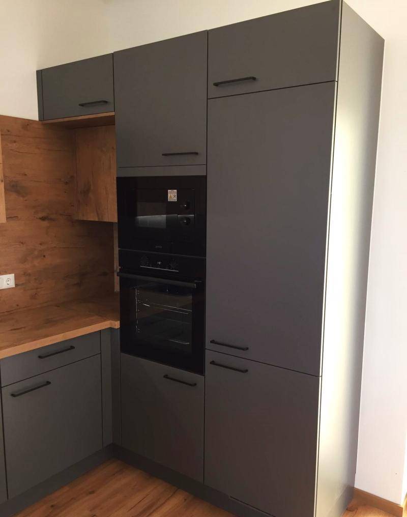 Hohe Küchenschränke in Grau mit integriertem Backofen und Mikrowelle, bieten viel Stauraum.