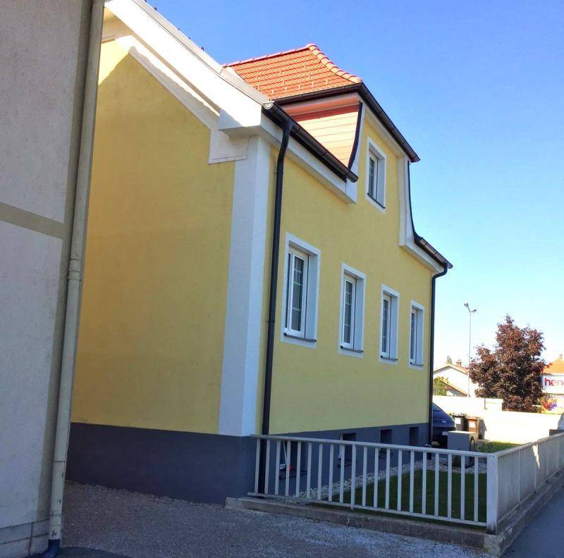 Ansicht des gelben Hauses mit klarem Himmel und gepflegter Außenfassade, die kürzlich renoviert wurde.