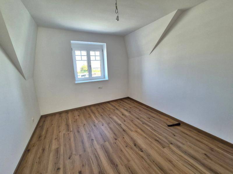 Geräumiges Schlafzimmer mit Laminatboden und Fenster mit Blick ins Grüne, ideal zum Entspannen.