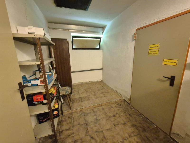 Einfacher Abstellraum im Keller mit Fliesenboden, Regalen und einem kleinen Fenster für Belüftung.