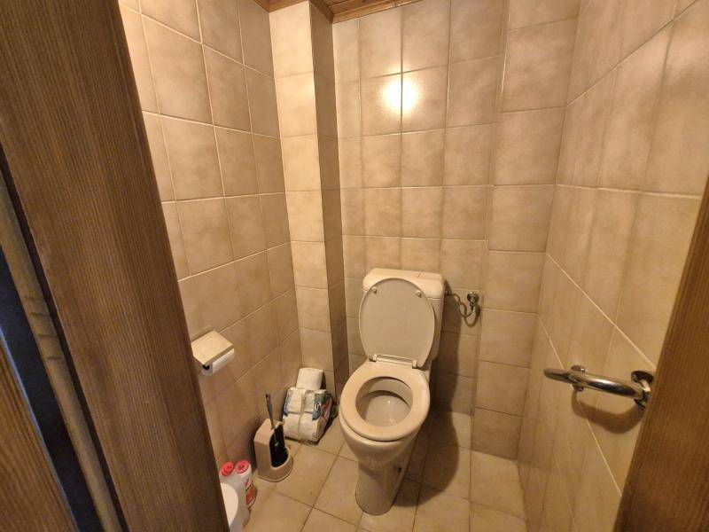 Separate Toilette mit beigefarbenen Fliesen und einem kleinen Fenster für Belüftung.