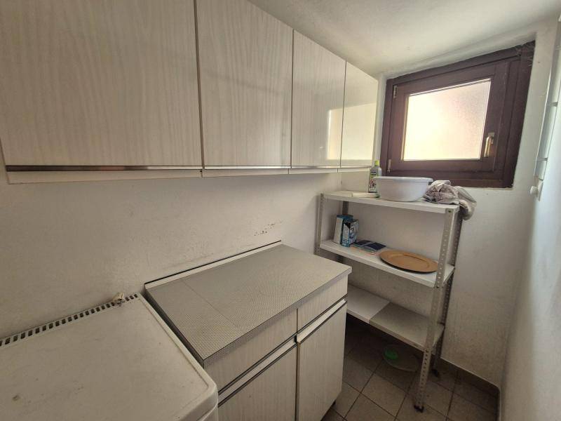 Kleiner Hauswirtschaftsbereich mit Hängeschränken, Regal und einem Fenster, ideal für zusätzliche Lagerung.