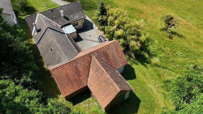 Nähere Luftaufnahme des Anwesens mit verschiedenen Gebäuden und Dächern, eingebettet in grüne Natur.