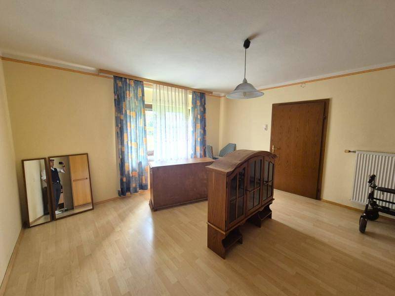 Geräumiges Zimmer mit Holzboden, einem Schreibtisch und bunten Vorhängen, ideal als Büro.