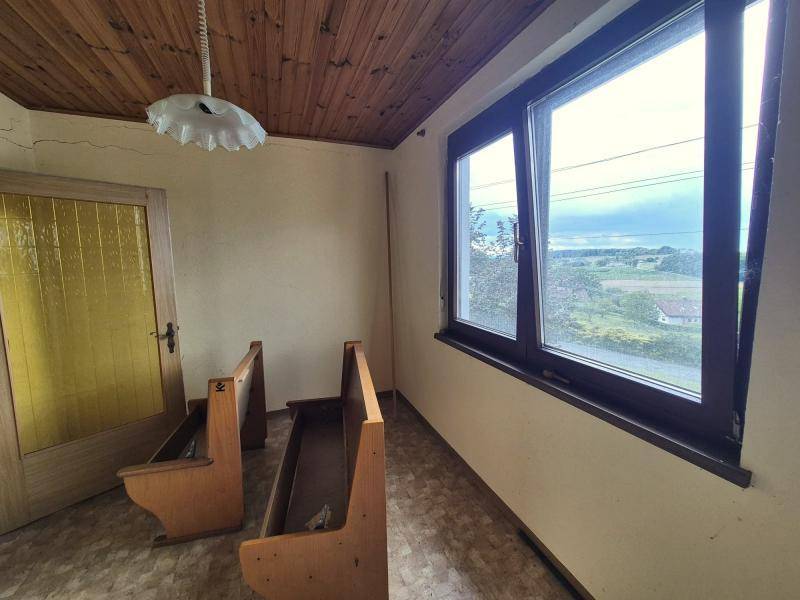 Lichtdurchfluteter Raum mit Holzdecke, großen Fenstern und einem weiten Blick auf die Landschaft.