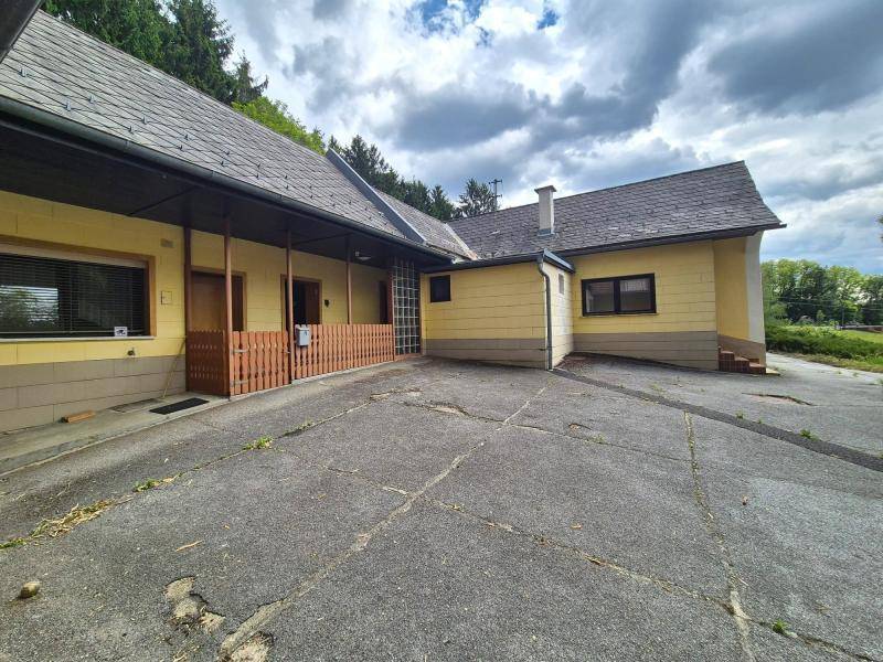 Eingangsbereich des Hauses mit überdachtem Zugang und einer großen gepflasterten Fläche davor.