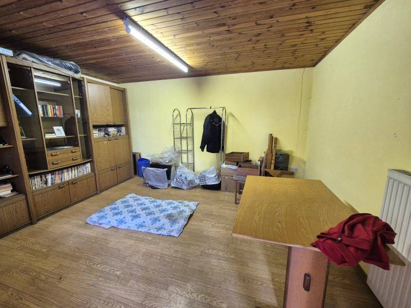 Wohnraum mit Holzdecke, Laminatboden und einem großen Schrank, der als Bücherregal dient.
