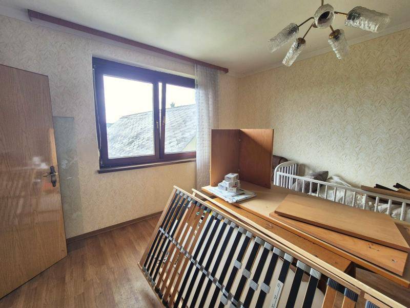 Schlafzimmer mit hellem Holzboden und einem Fenster, das viel Tageslicht hereinlässt.