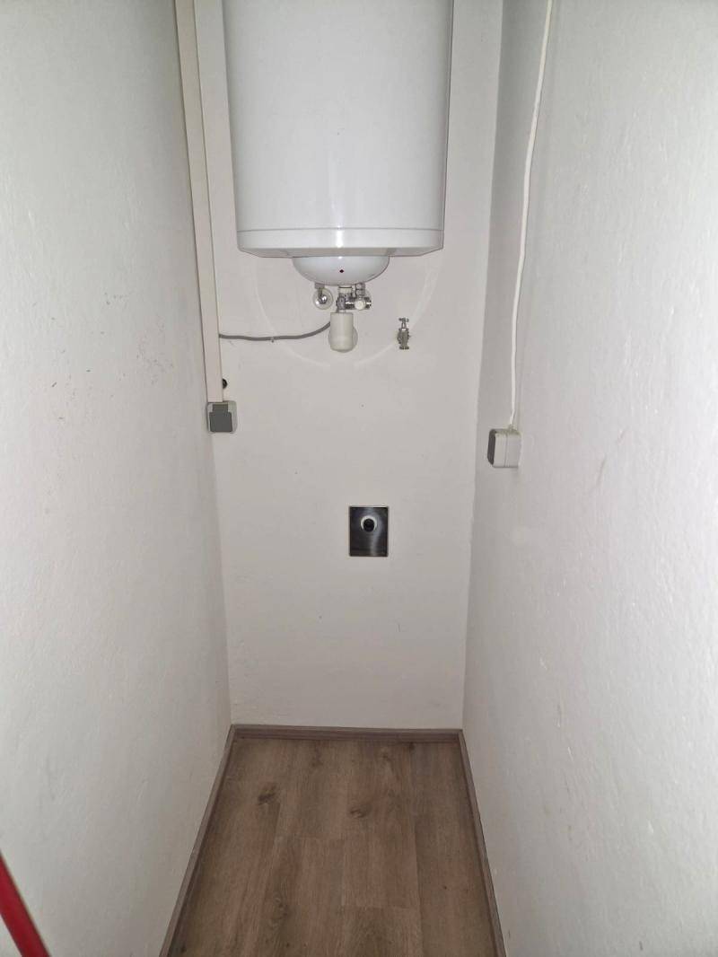 Kleiner Abstellraum mit Warmwasserboiler und Anschlüssen, ideal für Waschmaschine oder Lagerung.
