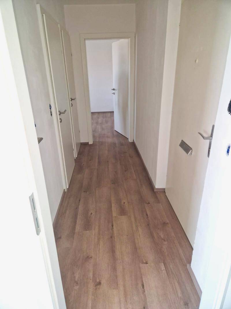 Heller Flur mit Laminatboden und mehreren Türen, der zu den verschiedenen Räumen führt.