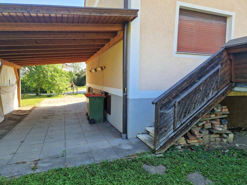 Überdachter Carport-Bereich mit gepflastertem Boden und Zugang zum Garten.