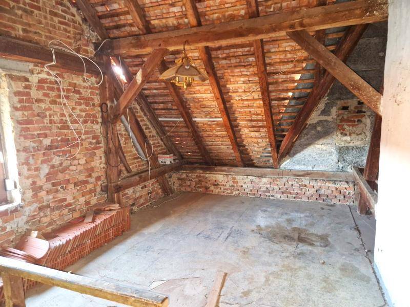 Unausgebauter Dachboden mit sichtbaren Holzbalken und Ziegelwänden, bereit für Ausbau.