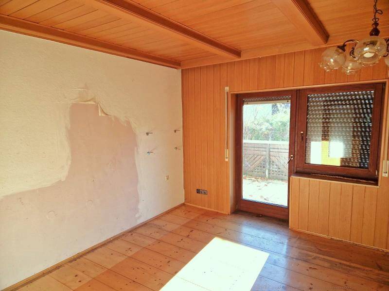 Leerer Raum mit Holzboden, Holzdecke und Zugang zu einem Außenbereich.