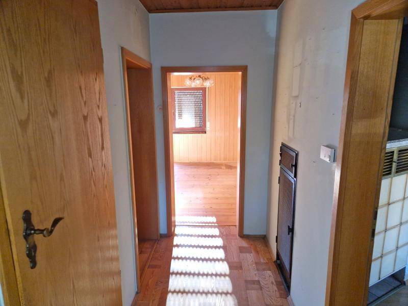 Heller Flur mit Holzboden und Holztäfelung an der Decke, der zu weiteren Räumen führt.