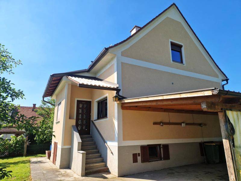 Seitenansicht des Hauses mit Eingangsbereich, Außentreppe und überdachtem Carport.