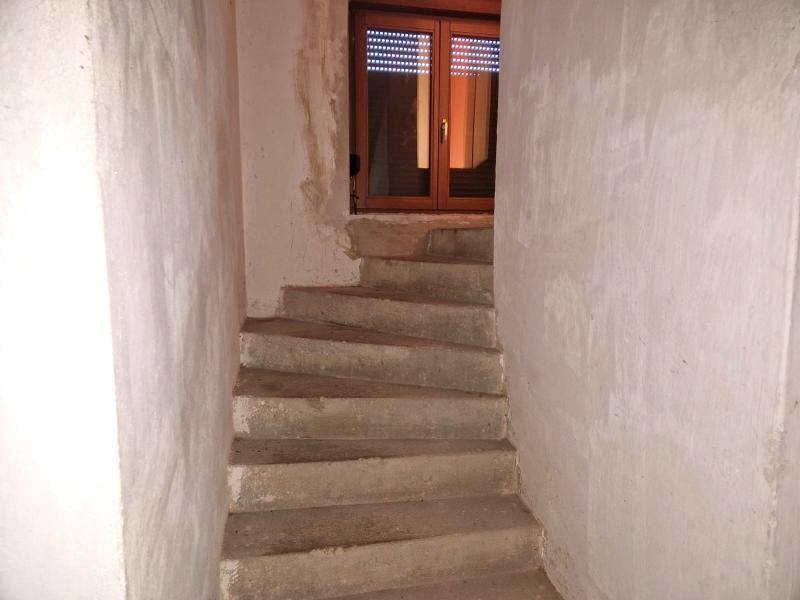 Betontreppe führt hinunter in den Kellerbereich mit einem Fenster am Ende.