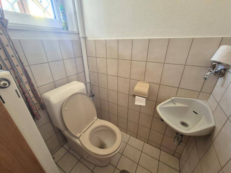 Kleines Gäste-WC mit Toilette und Eckwaschbecken, funktional und platzsparend gestaltet.