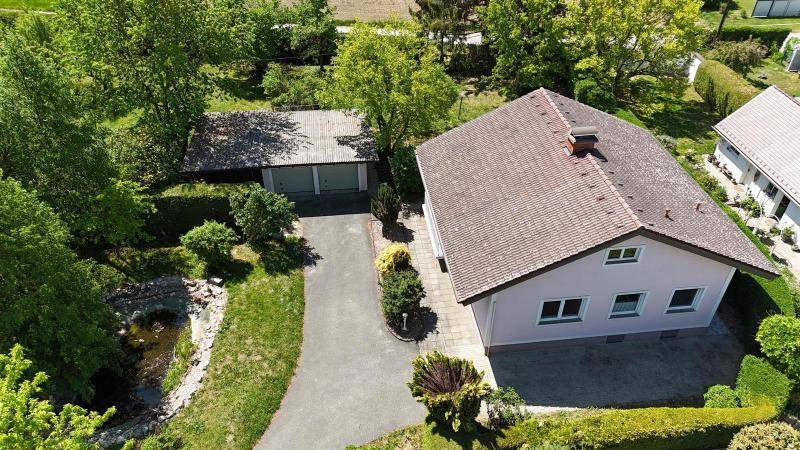 Überblick aus der Vogelperspektive mit Einfamilienhaus, Garage, Zufahrt und weitläufigem Grün.