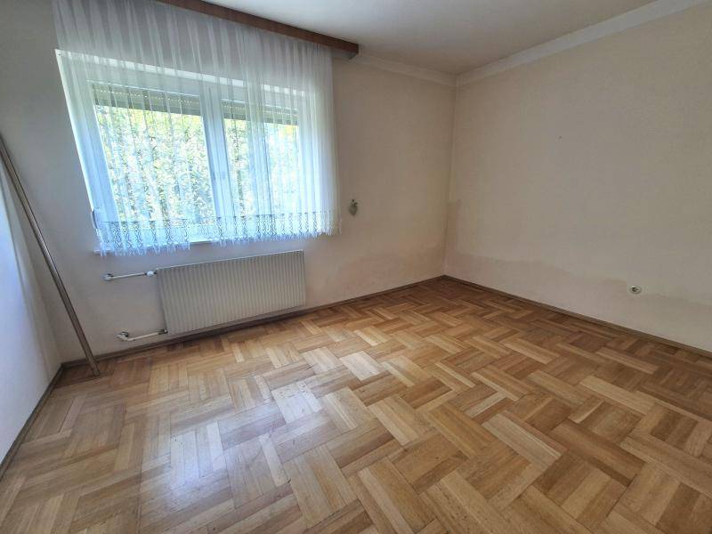 Helles Zimmer mit Parkettboden, großem Fenster und Heizkörper, ideal für Schlaf- oder Arbeitszimmer.