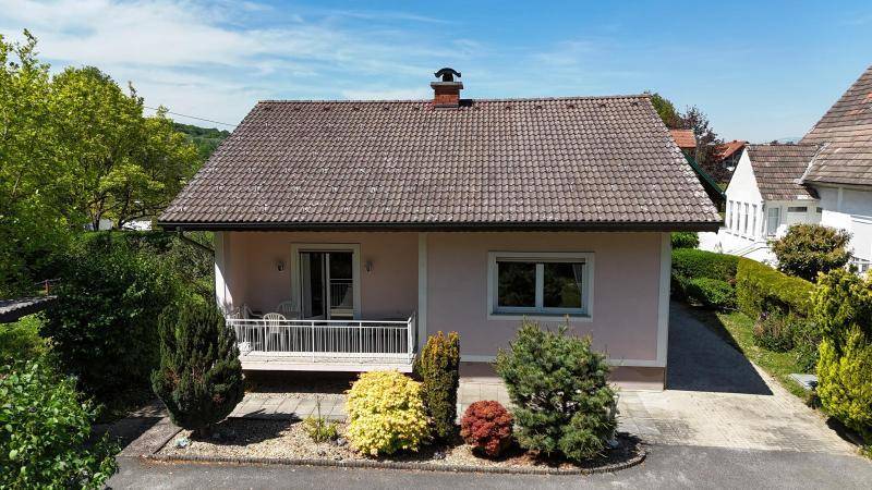 Vorderansicht des Einfamilienhauses mit kleinem Balkon und gepflegter Vorgartenbepflanzung.