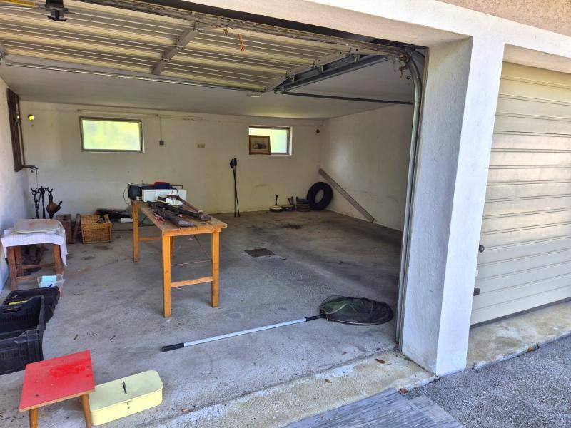Geräumige Garage mit Betonboden und offenem Garagentor, bietet Platz für Fahrzeuge und Lagerung.