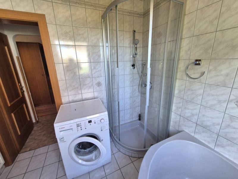 Badezimmer mit Waschmaschine, Duschkabine und Eckbadewanne, praktisch und funktional eingerichtet.