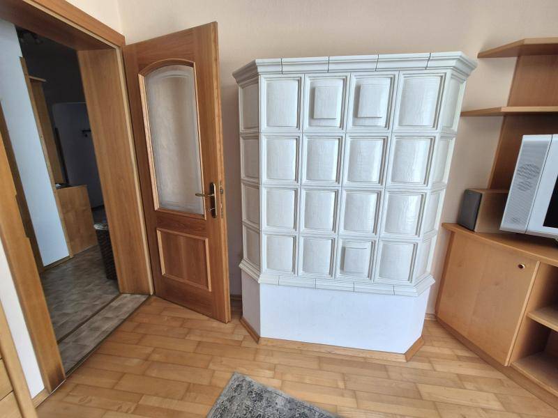 Detailansicht des eleganten weißen Kachelofens im Wohnzimmer, der Wärme spendet.