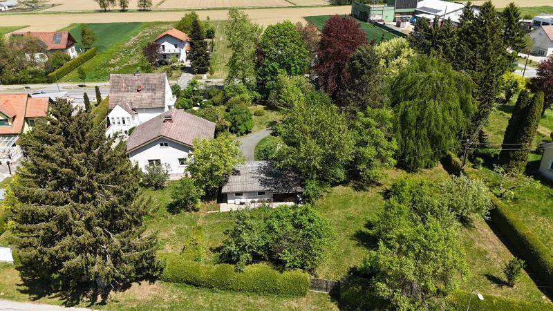 Luftaufnahme eines Anwesens mit großem Garten, umgeben von Feldern und Wohnhäusern.