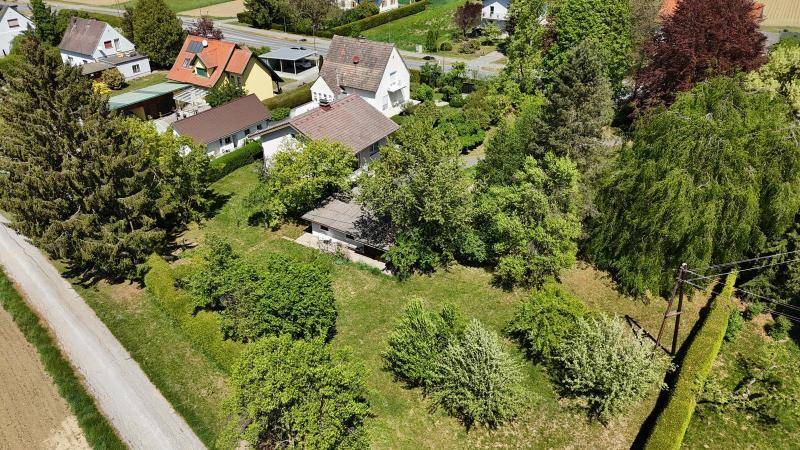 Überblick aus der Vogelperspektive über das weitläufige Grundstück mit viel Grün und angrenzenden Feldern.