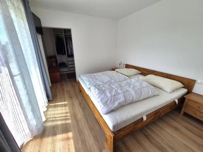 Schlafzimmer mit Holzbett, Holzboden und Zugang zu einem begehbaren Kleiderschrank.