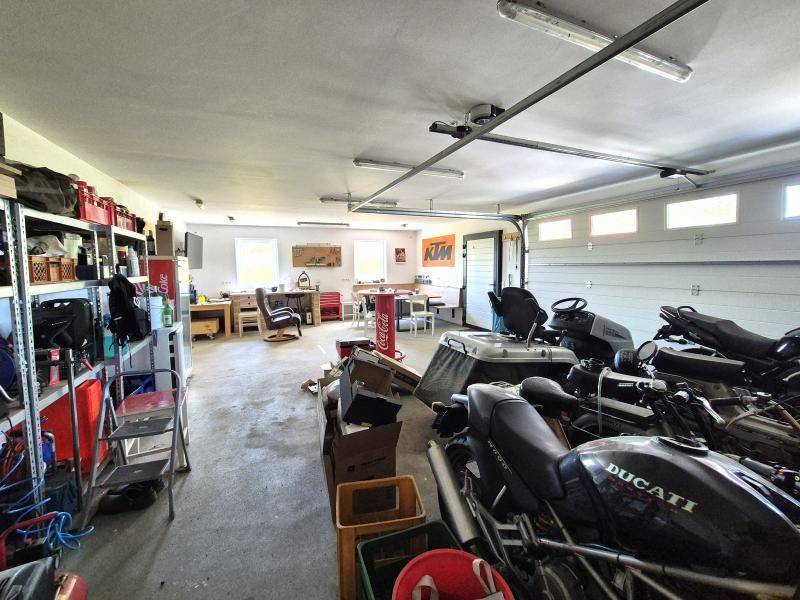 Geräumige Garage mit Platz für Fahrzeuge, Werkstattbereich und einer gemütlichen Sitzecke im Hintergrund.