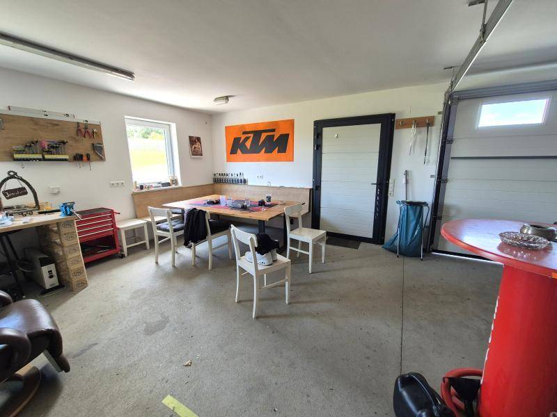 Helle Garage mit Werkbank, Sitzgelegenheiten und großem Garagentor, perfekt für Arbeiten und Freizeit.