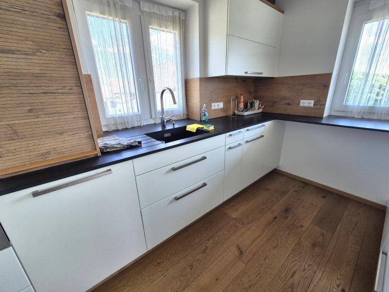 Funktional gestaltete Küche mit Spülbecken, dunkler Arbeitsplatte und Holzboden.