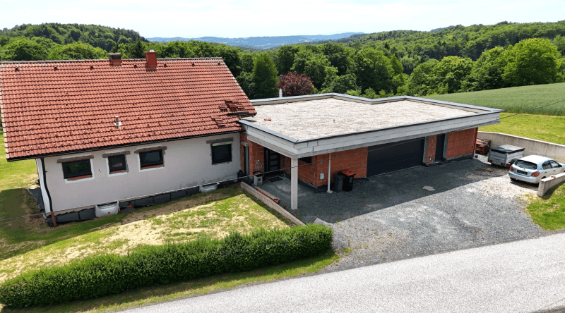 Seitenansicht des Hauses mit Zufahrt und Anbau, eingebettet in die ländliche Umgebung.