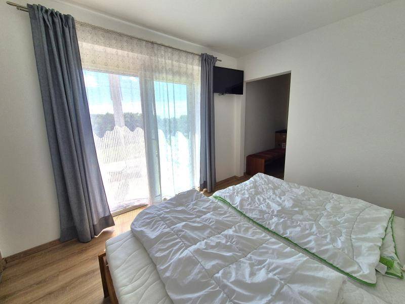 Schlafzimmer mit Zugang zum Balkon, Holzboden und Fernseher.